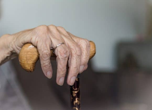 Elderly hand resting on cane