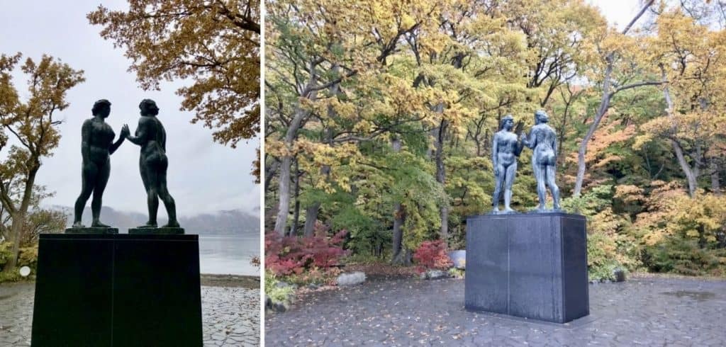 Statues of 2 women nearly touching hands beside Lake Towada.