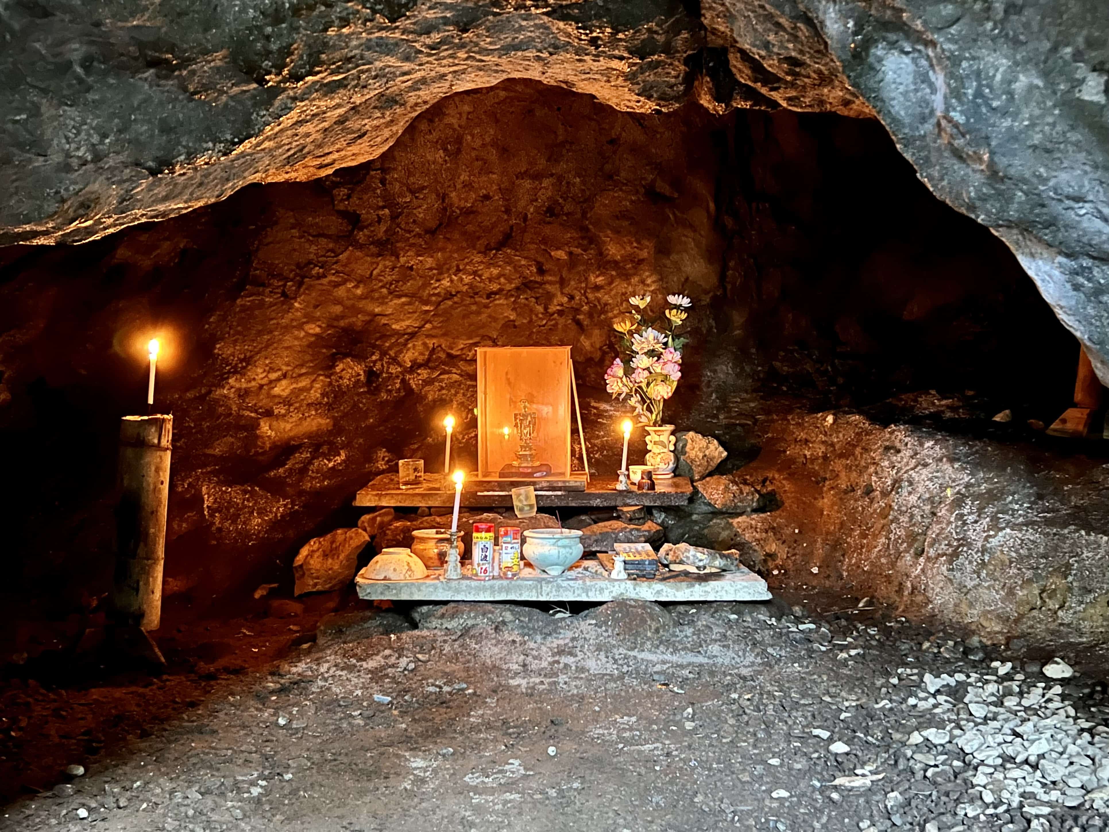 Hidden Buddhist cave with altar lit by candles.