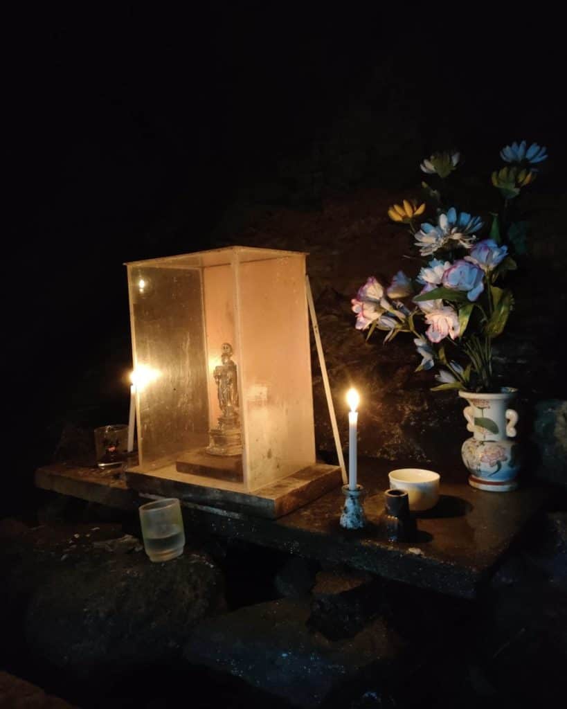 Amida Nyorai statue in Kakure Nenbutsu cave, lit by candles.