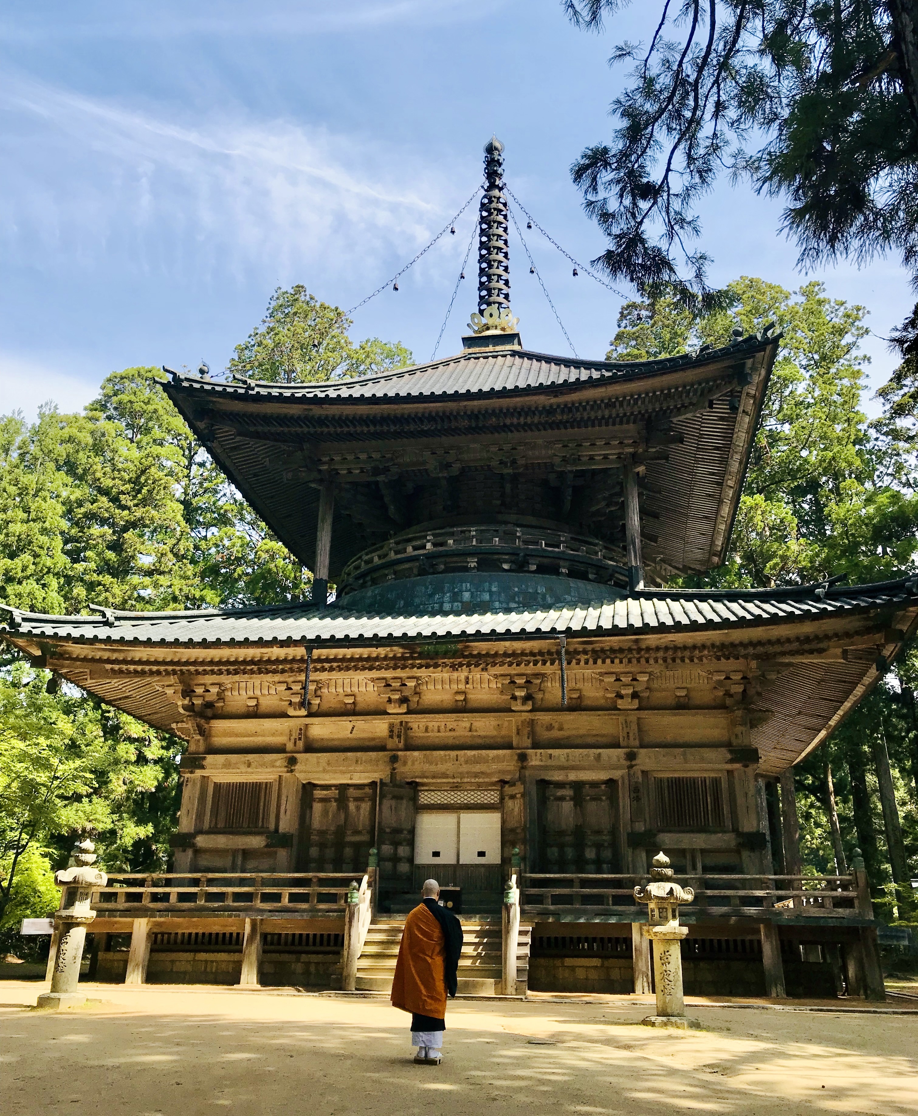 Monk standing before a two-story pagoda on Mount Koya.