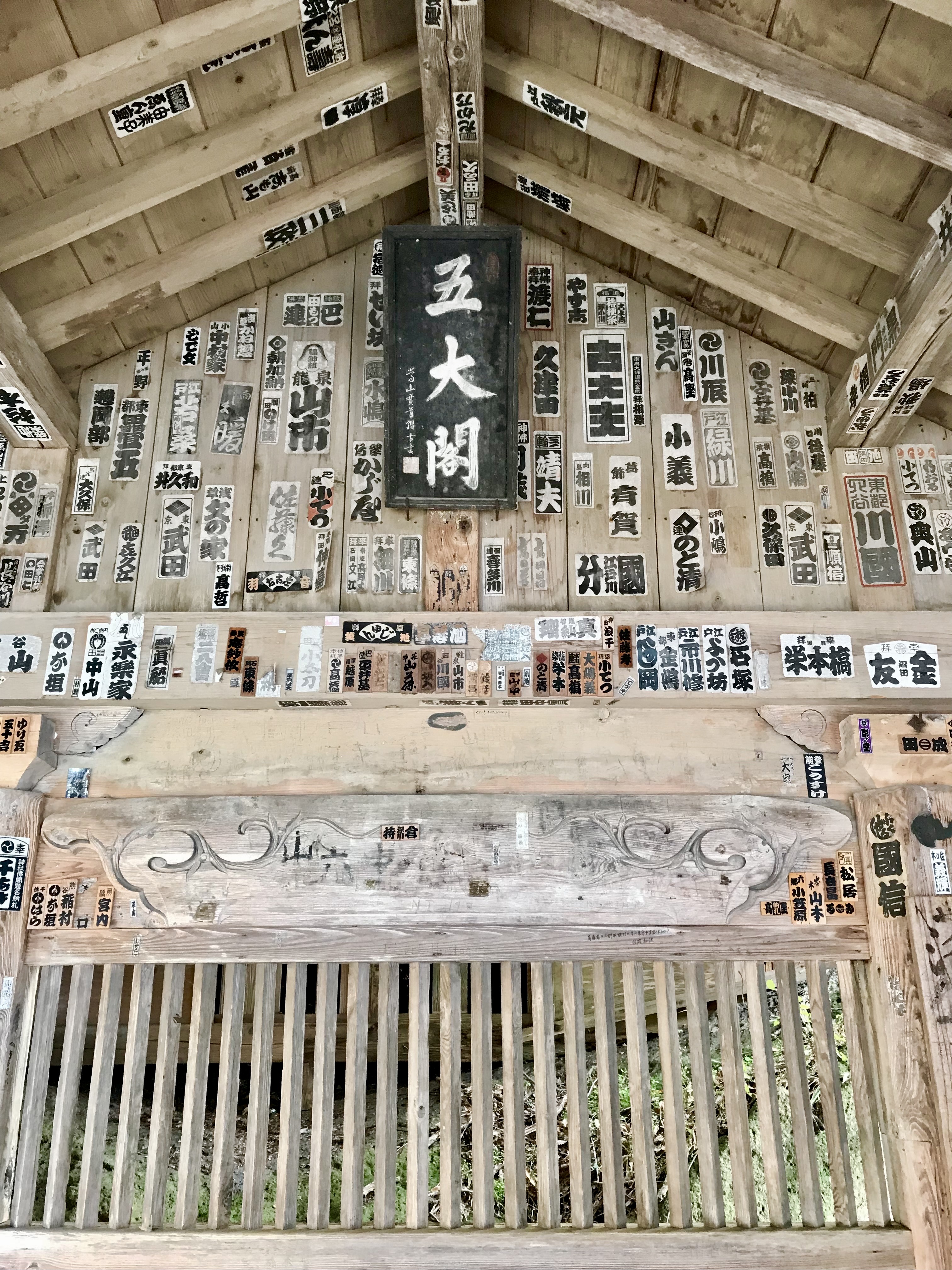 Walls and ceiling of temple on Yamadera covered with senjafuda stickers.