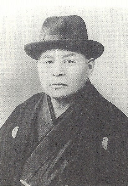 Black and white photo of Endo Genmu in kimono and western-style hat.