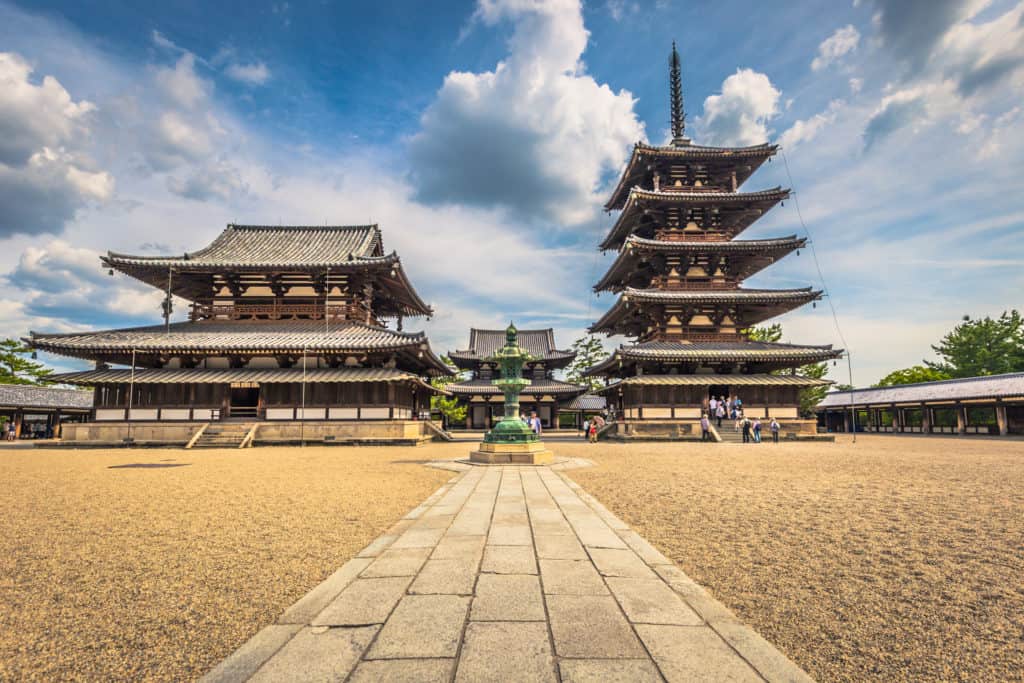 Ancient wooden temple and pagoda standing side by side and backed by dynamic clouds.