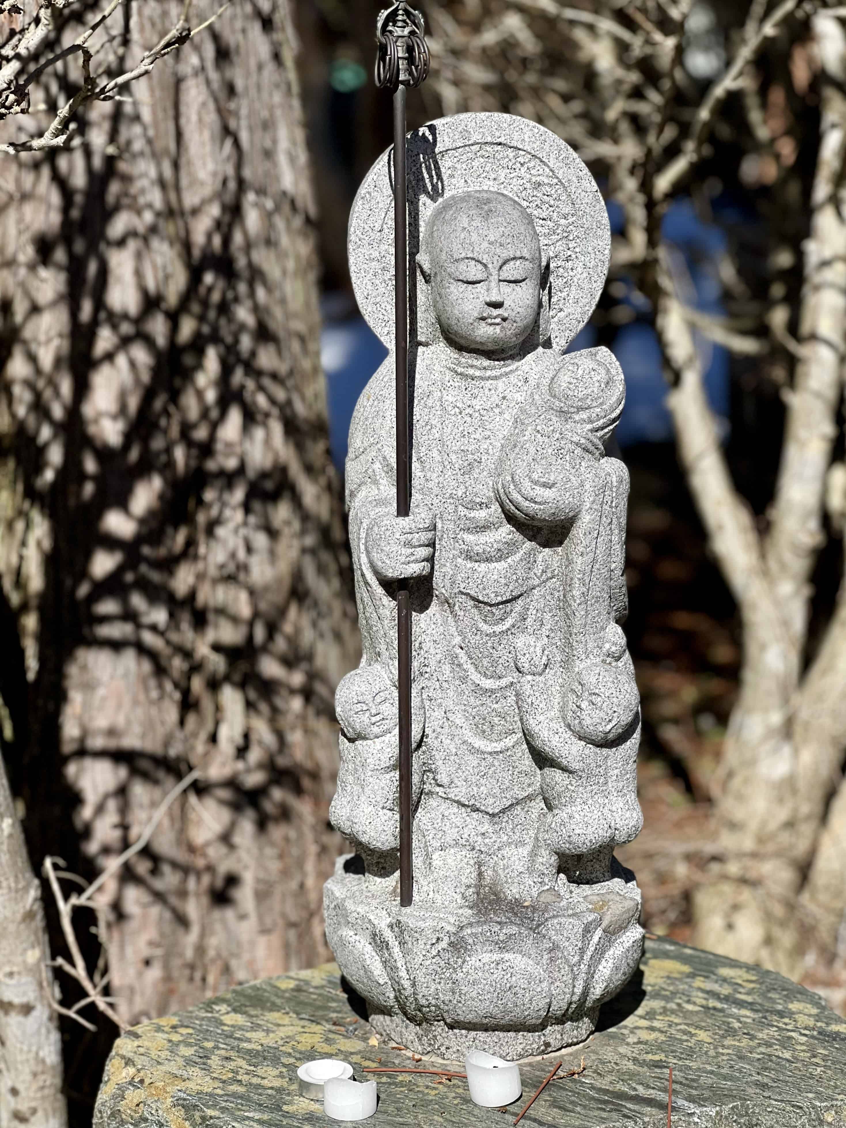 Buddhist Jizo statue holding a baby, with two other babies grabbing at his robes.