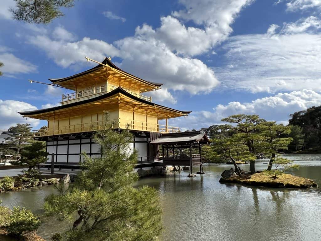The Golden Pavilion in Kyoto against a blue cloudy sky.
