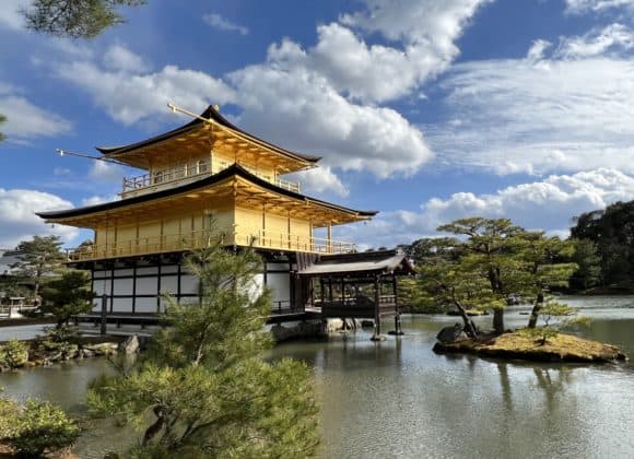 The Golden Pavilion in Kyoto against a blue cloudy sky.