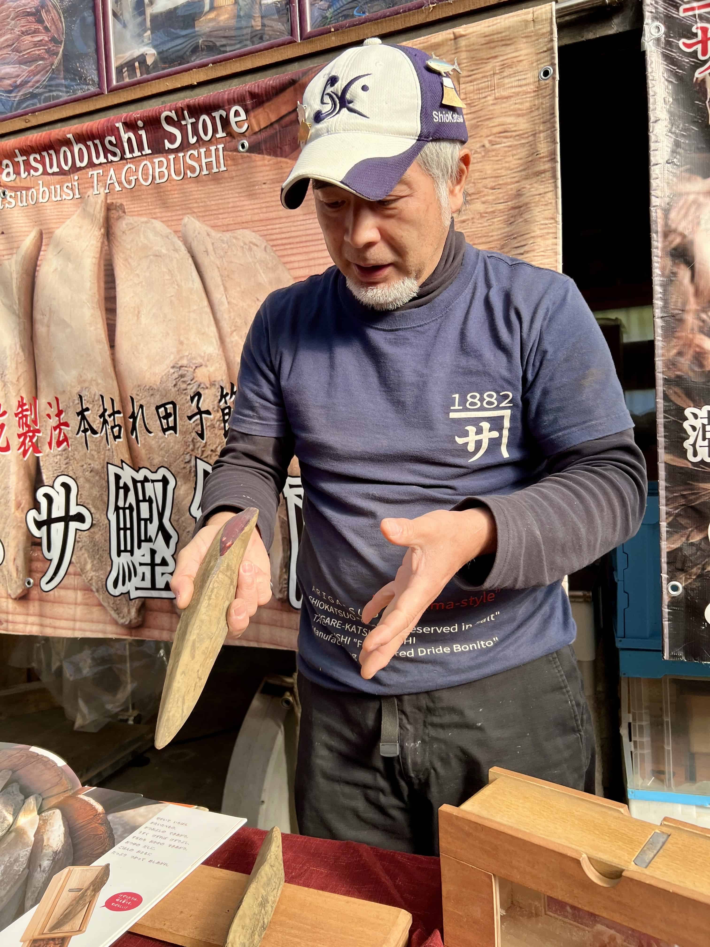Man holding a dried bonito, showing the deep red interior.