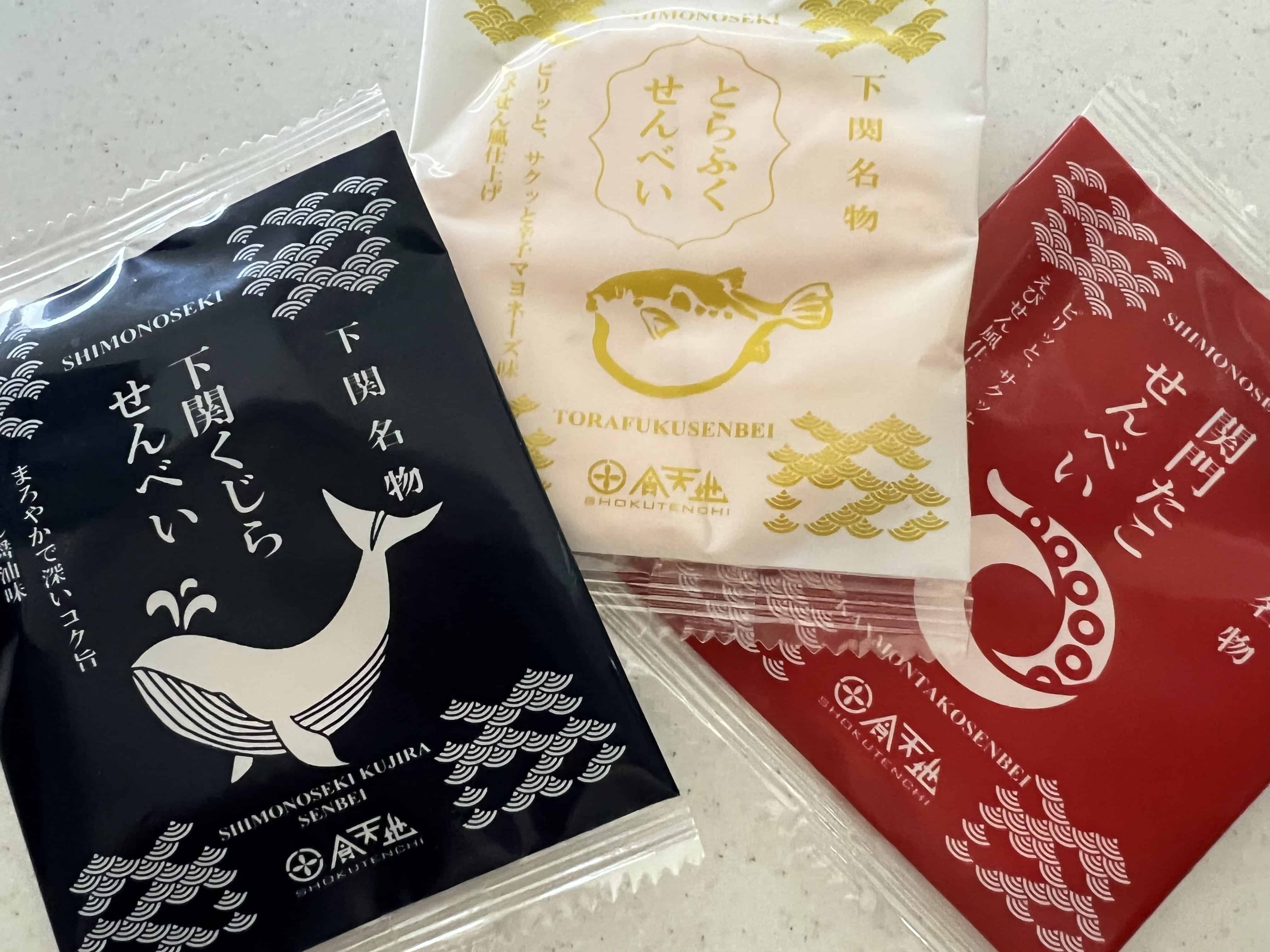 Three packages of rice crackers with drawings of a whale, a blowfish, and an octopus leg on them.