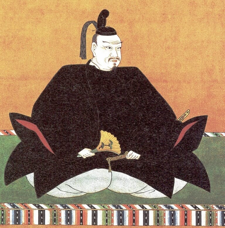 Mori Terumoto, sitting on a cushion wearing many layers of kimono and a traditional hat.